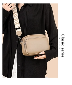 Detail of trendy crossbody bag with dual-zipper layers and geometric woven shoulder strap
