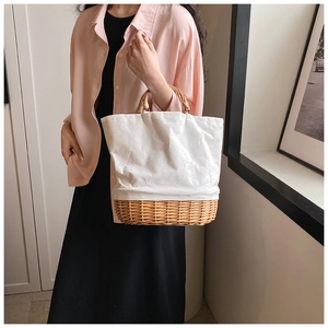 Close-up of stylish straw woven and white canvas patchwork design on a lady handbag