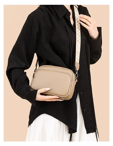 Detail view of khaki pebbled leather crossbody bag with a colorful woven wide strap