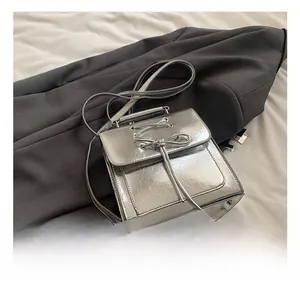 Detail of silver PU leather backpack with drawstring bow and polished metallic finish