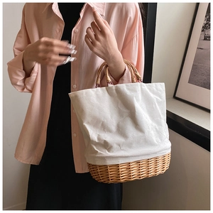 Detailed shot of straw woven and white canvas patchwork handbag with round cane handles