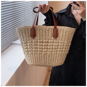 Détail macro du sac cabas en paille avec motifs évidés élégants et poignée en cuir chic