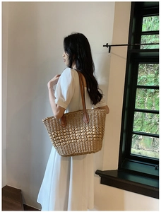Détail du sac cabas en paille tissé à la main avec bandoulière en cuir par un mannequin