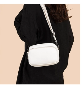 Detail view of white lychee texture camera bag with geometric woven wide shoulder strap