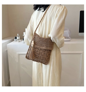 Detail of woven straw crossbody bag with decorative tassels and wooden beads on side