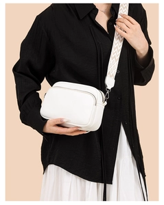 Detail of white litchi pattern bag with embroidered geometric wide strap worn on shoulder