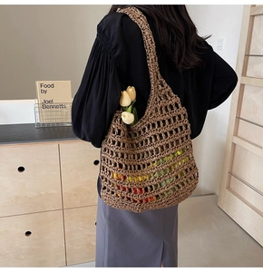 Deep brown hand-woven straw mesh tote bag worn by a model in a minimalist interior setting