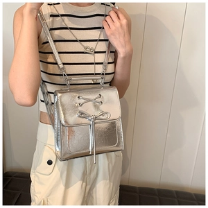 Close-up of metallic silver PU backpack featuring decorative cross lacing and bow detail