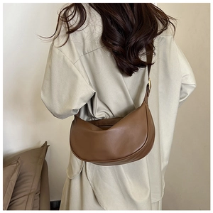 Detail of a brown PU leather half-moon crossbody bag with adjustable strap and gold hardware