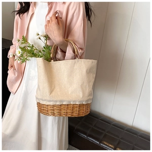 Detailed shot of woman carrying canvas straw tote bag with bamboo handles and daisy floral accent