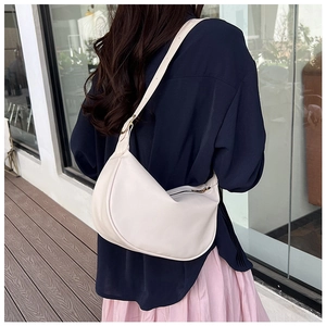Chic beige half-moon PU leather crossbody bag worn on shoulder for minimalist daily outfit