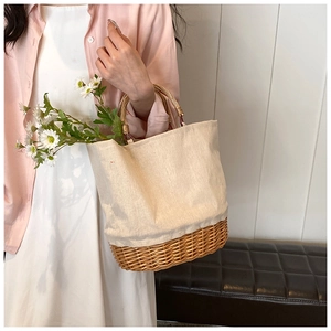 Detail of hand-woven straw and canvas tote bag with round bamboo handles for women