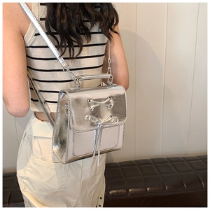 Silver metallic PU backpack with bow detail and adjustable straps on a model back