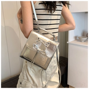 Detail of silver metallic textured crossbody bag with bow tie design and chain handle