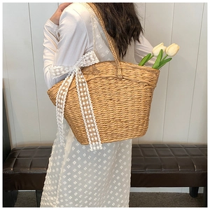 Detail shot of hand-woven straw tote bag with white lace bow and elegant tulip decoration