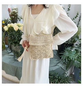 Detail of beige straw crossbody bag with shell pattern crochet and tassel decoration