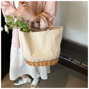 Detailed shot of straw woven shoulder bag with canvas panels and round wooden handle