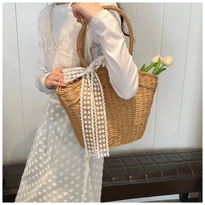 Detail of hand-woven straw shoulder bag featuring a large white lace bow decoration