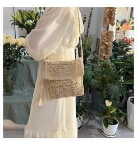 Detail of light beige woven crossbody bag with stylish wood bead tassels and wavy texture