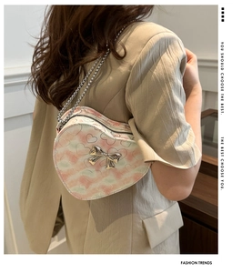 Détail du sac à bandoulière en forme de cœur avec imprimé tie-dye et nœud en métal doré