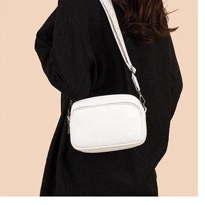 White PU leather crossbody camera bag with black and white geometric woven strap on model