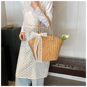 Detail of straw woven tote bag featuring white lace bow and decorative tulips