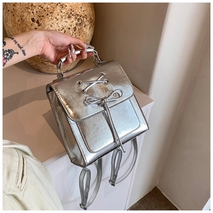 Detail of silver metallic PU backpack featuring cross-lacing and bow design with metal handle