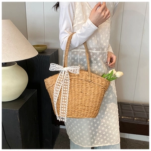 Detail of straw woven handbag with white lace bow and floral garden aesthetic