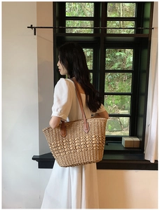 Détail du sac cabas en paille tissée avec poignées en cuir marron et motifs texturés