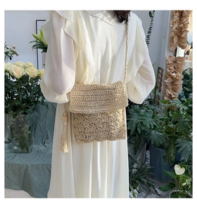 Close-up of beige woven straw crossbody bag with tassel detail on a female model