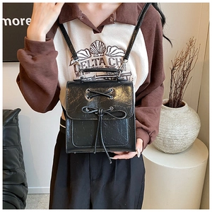 Detail showing black cracked PU leather backpack with decorative ribbon bow and drawstring