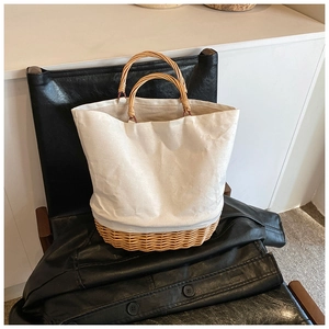 Minimalist straw woven tote bag with white canvas panel on a leather seat