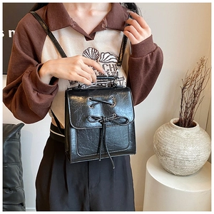 Detail of black vintage PU backpack featuring bow tie design and textured finish
