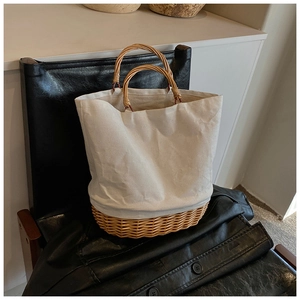 Minimalist straw and canvas patchwork tote bag with woven handles on a leather chair