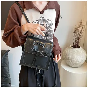 Detail of black faux leather crossbody bag with bow decoration and pleated texture finish