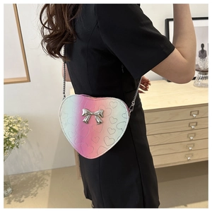Détail du sac bandoulière cœur dégradé avec nœud argenté porté par un mannequin