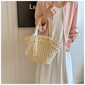 Detail of handwoven straw tote bag with elegant white lace ribbon handle decoration