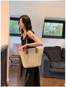 Détail du sac cabas en paille avec texture tissée serrée et bandoulière en cuir brun