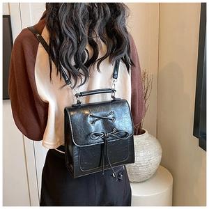 Detail of a black PU leather backpack featuring retro cross-lacing and a sweet bow design