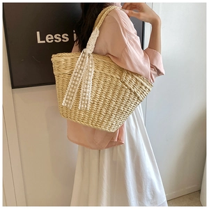 Detail of woven straw tote bag with elegant white lace ribbons and textured shoulder strap