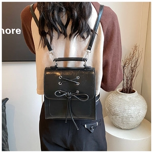 Detail of black PU leather backpack featuring chic bow tie flap and slim straps