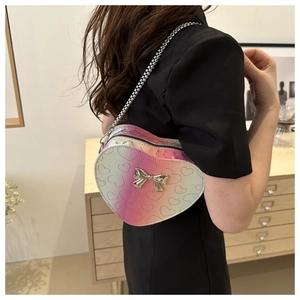 Détail d'un sac bandoulière en forme de cœur avec dégradé de couleurs et nœud en métal