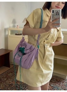 Gros plan d'un sac à bandoulière en nylon lilas avec des détails de cordon vert