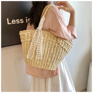 Detailed close-up of woven straw shoulder bag featuring white daisy lace ribbon accents