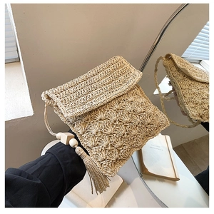 Beige woven straw crossbody bag with flap design and wooden bead tassel detail