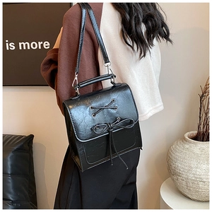 Close-up of black PU leather backpack with vintage texture and bow tie details