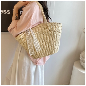 Straw woven tote bag detail featuring white floral lace decoration and natural texture