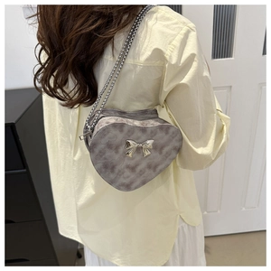 Détail du sac à bandoulière gris en forme de cœur avec nœud argenté et chaîne métal