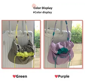 Détail des sacs bandoulière en nylon vert et violet sur une poignée de valise