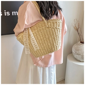 Detail of hand-woven beige straw tote bag with elegant white lace ribbons and shoulder strap